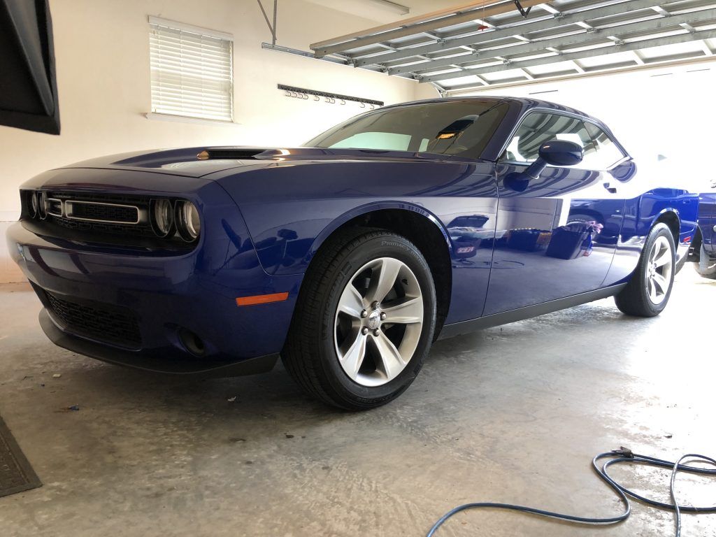 A blue dodge challenger is parked in a garage.