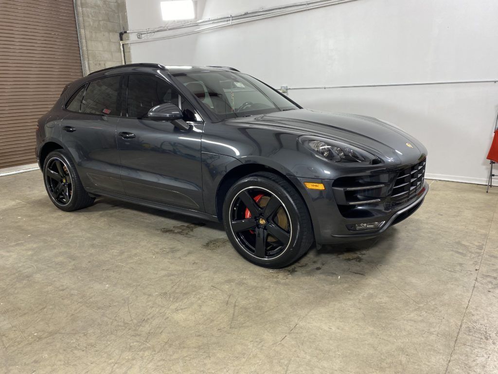 A gray porsche macan turbo is parked in a garage.