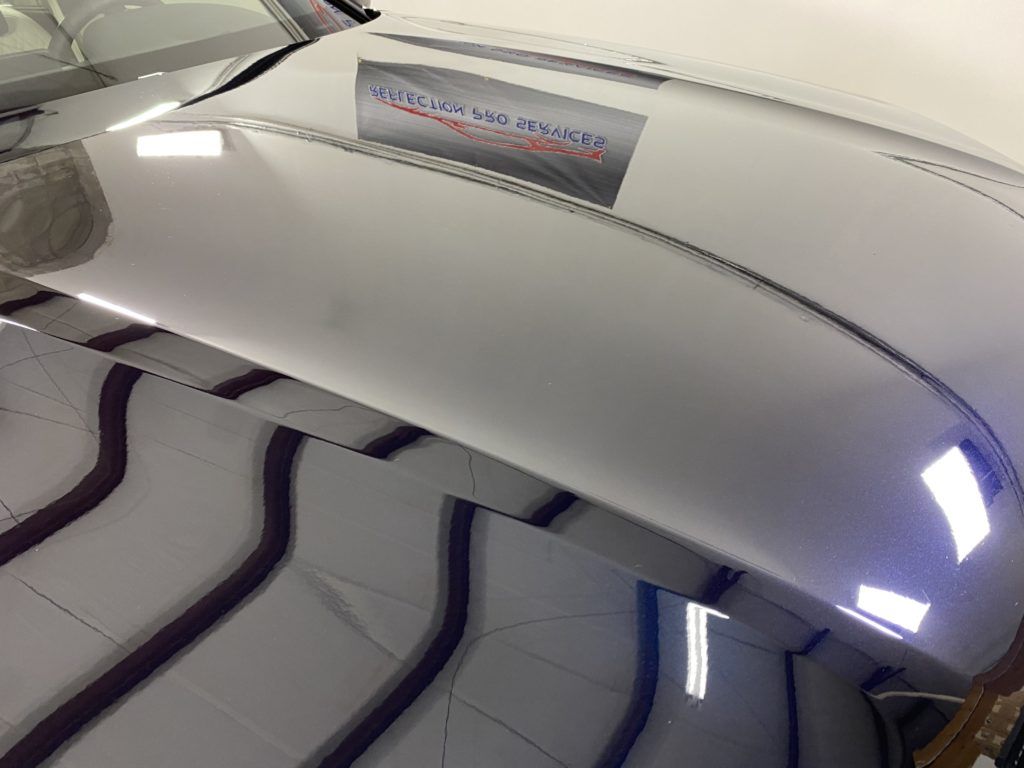 The hood of a car is reflected in a mirror.