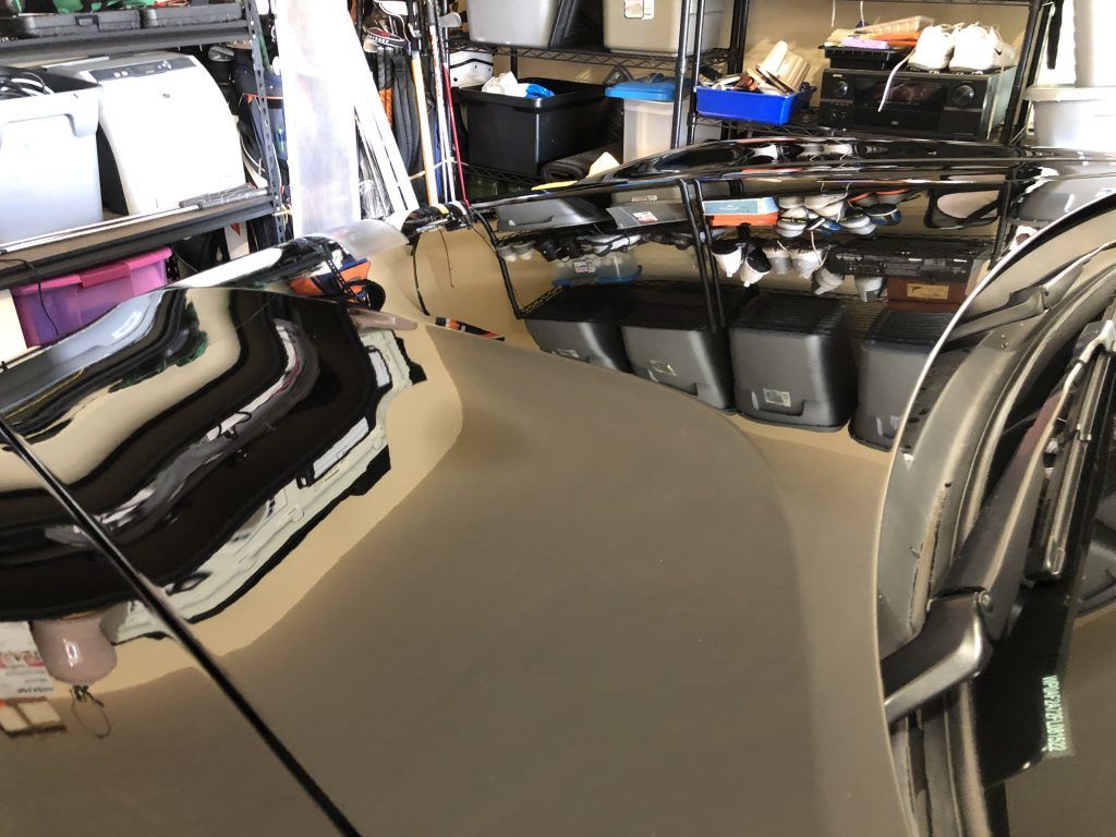 A car is parked in a garage with a reflection of it in the mirror.