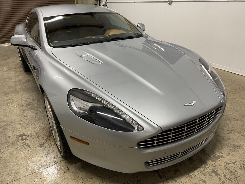 A silver sports car is parked in a garage next to a garage door.