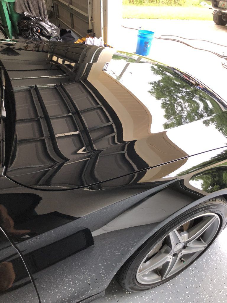 A black sports car is parked in a garage.