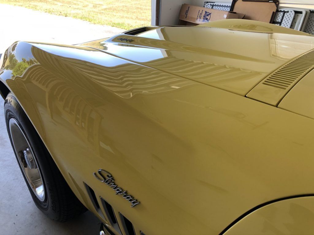 A yellow corvette is parked in a garage