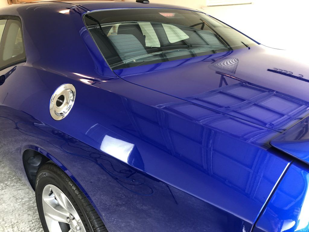 A blue car is parked in a garage with the hood up