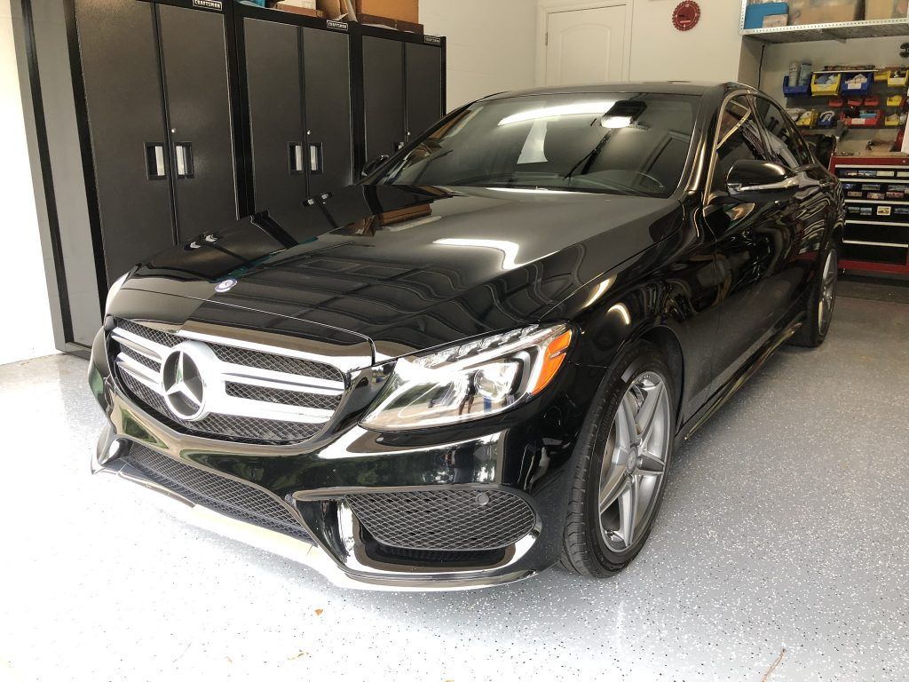 A black mercedes benz is parked in a garage.