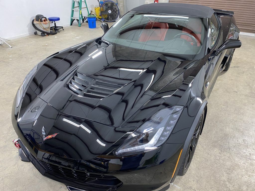 A black corvette convertible is parked in a garage.
