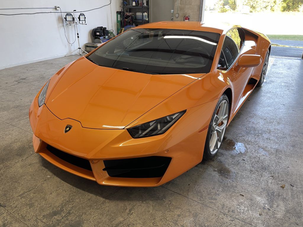 An orange lamborghini huracan is parked in a garage.