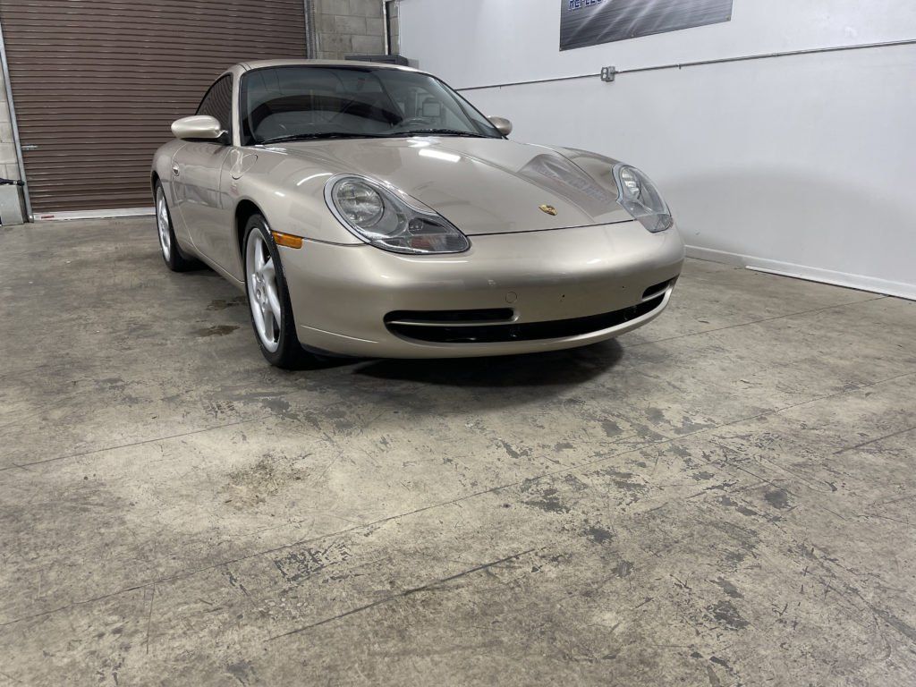 A gold porsche 911 carrera is parked in a garage.