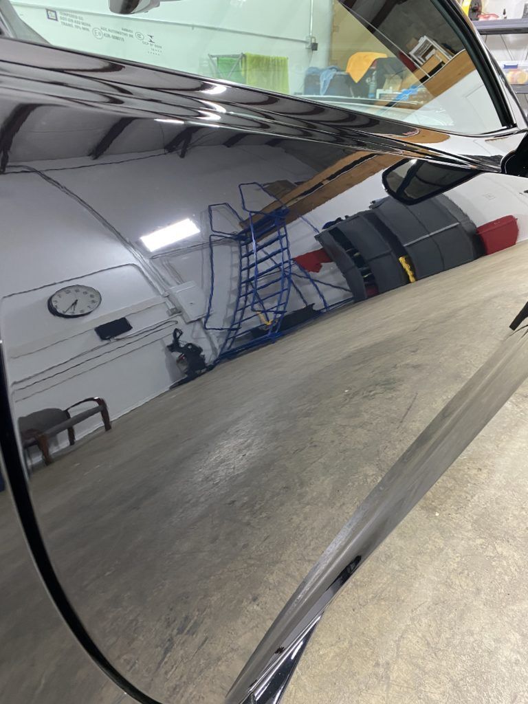 A car is reflected in a mirror in a garage.