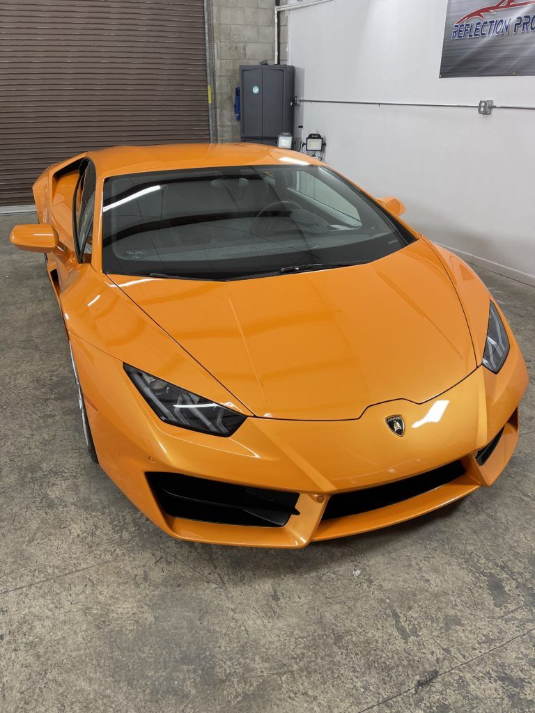 An orange lamborghini huracan is parked in a garage.