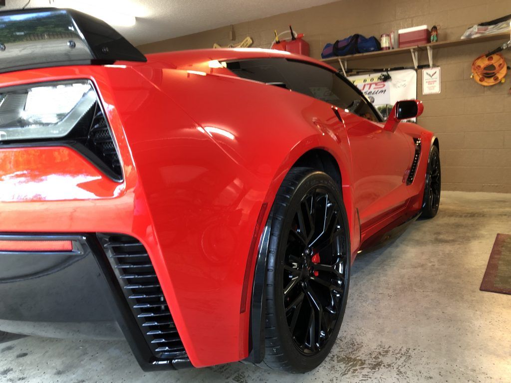 A red sports car is parked in a garage.