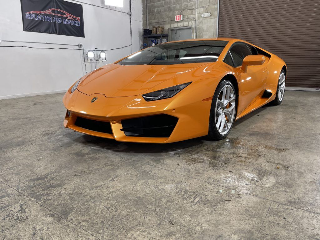 An orange lamborghini huracan is parked in a garage.