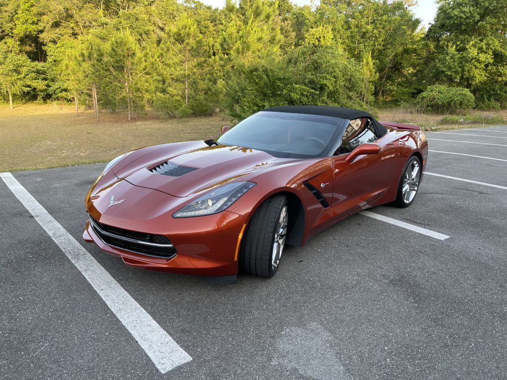 A red corvette convertible is parked in a parking lot.