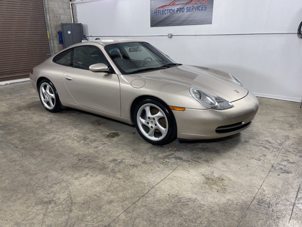 A silver porsche 911 is parked in a garage.