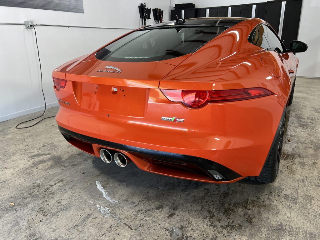A red jaguar f type is parked in a garage.