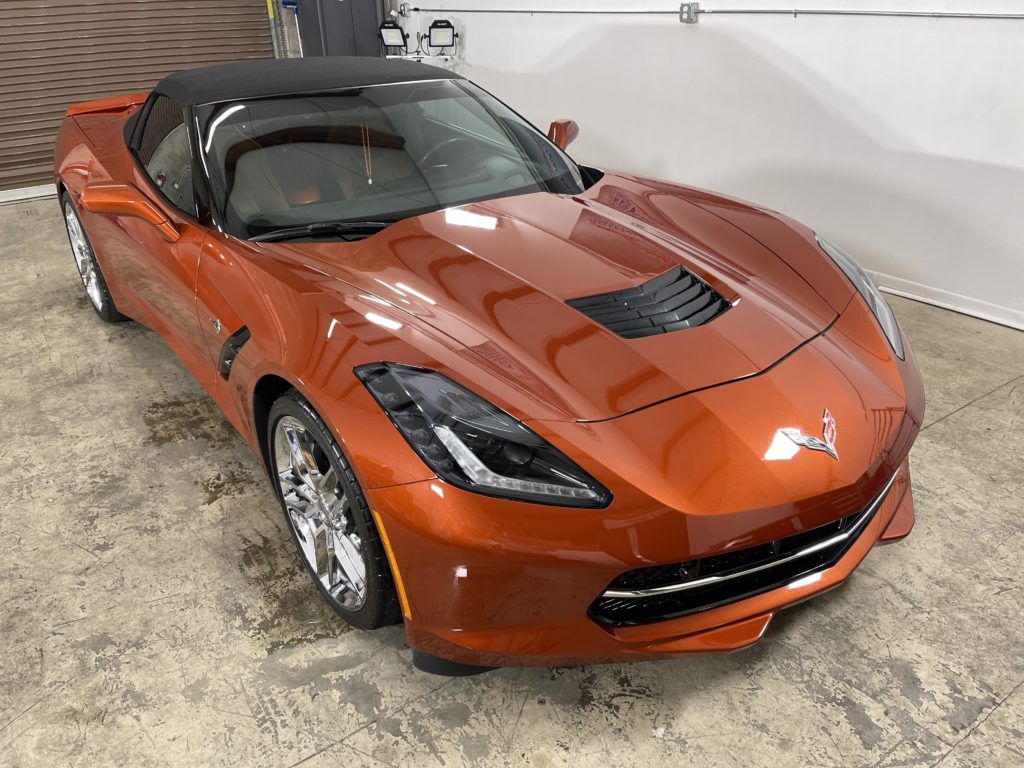 A red corvette convertible is parked in a garage.