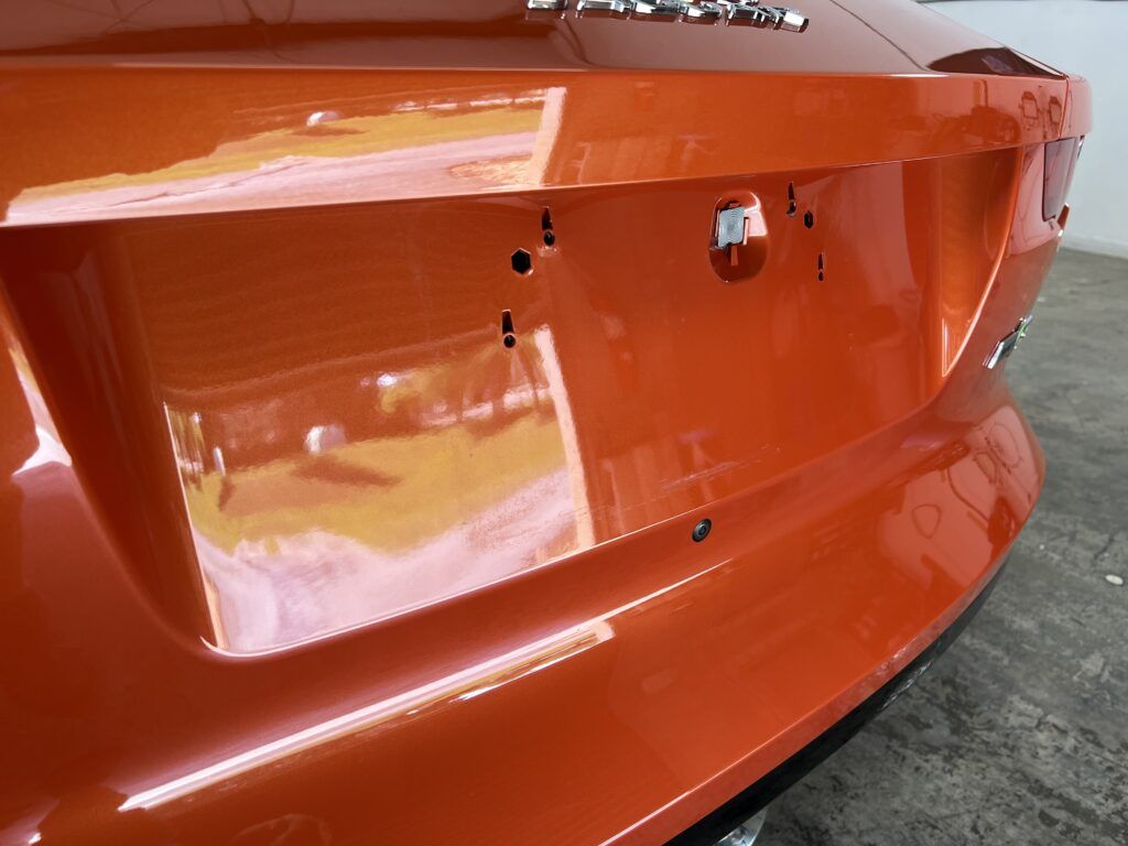 A close up of the back of an orange car in a garage.