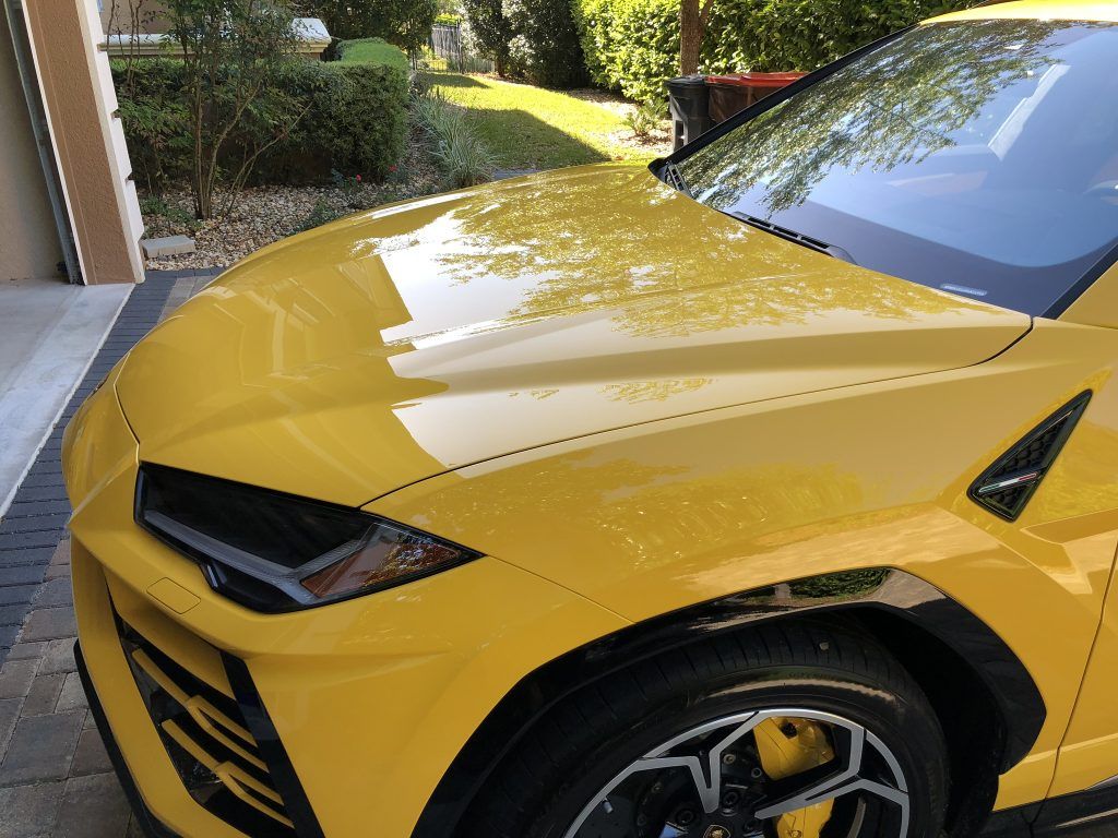 A yellow lamborghini urus is parked in a garage.