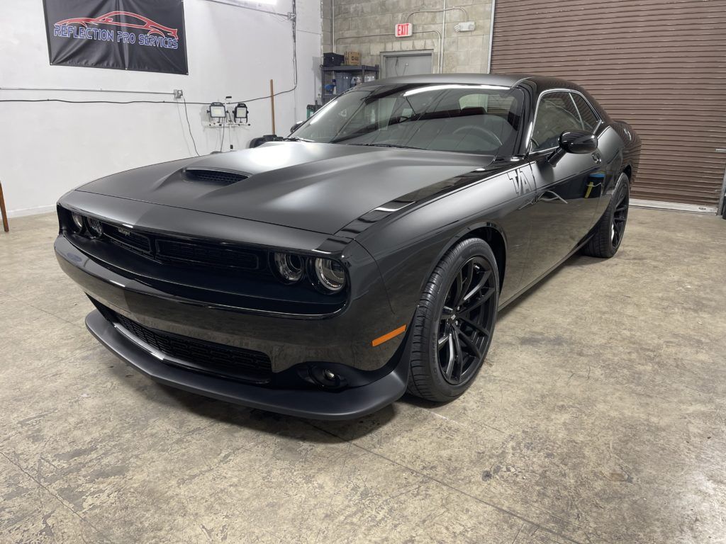 A black dodge challenger is parked in a garage.