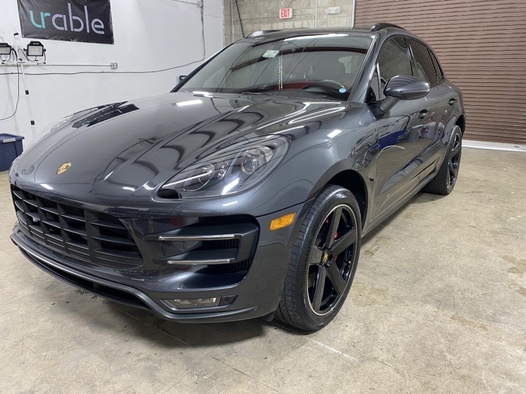 A gray porsche macan turbo is parked in a garage.