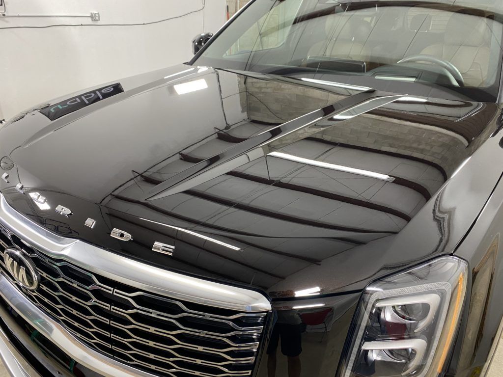 The hood of a black suv is sitting in a garage.