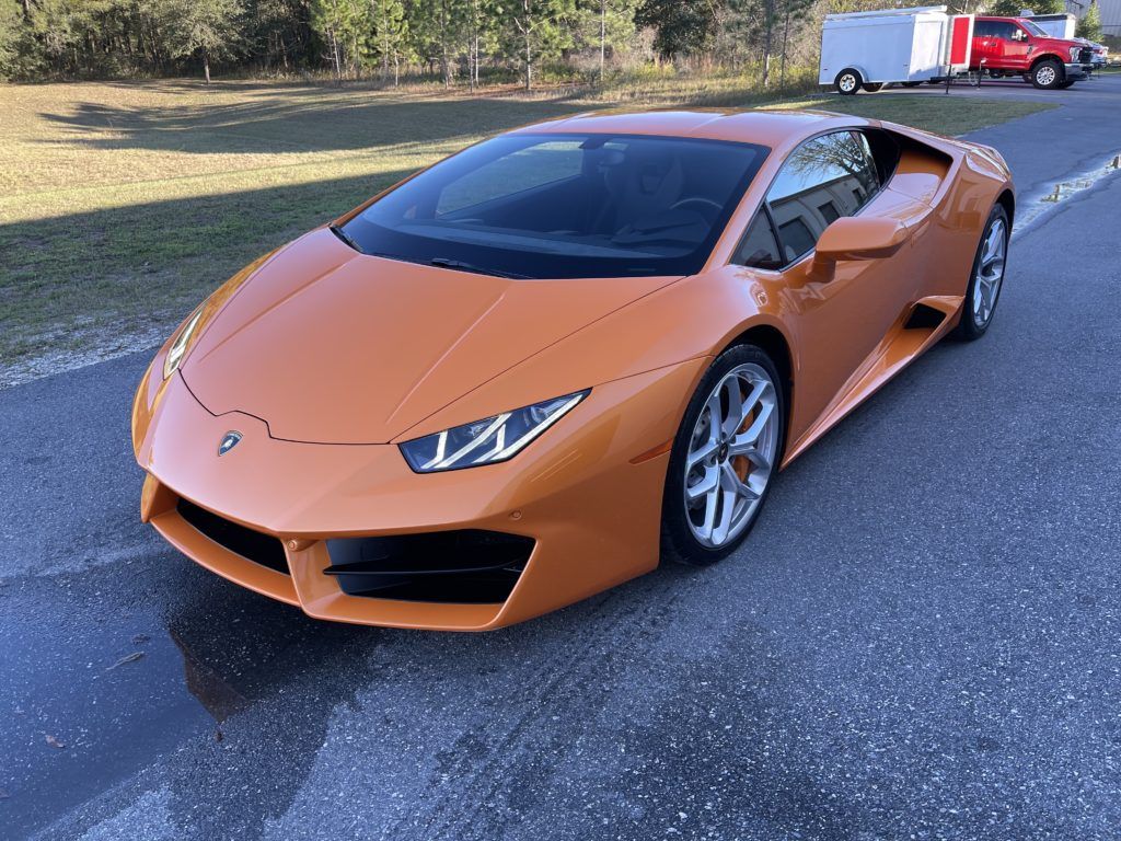 An orange lamborghini huracan is parked on the side of the road.