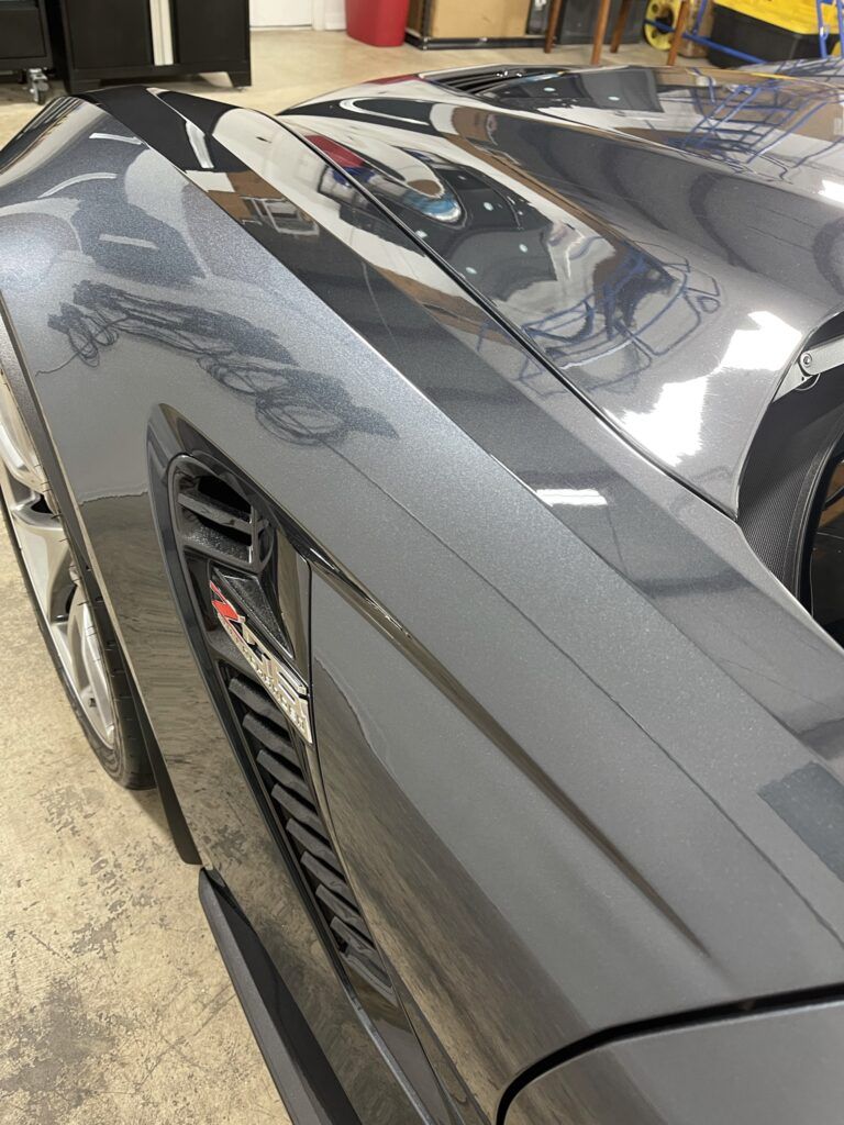 A close up of a black car 's fender in a garage.