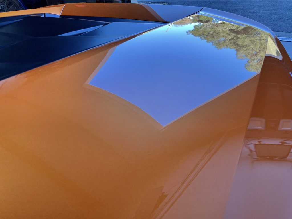 A close up of the hood of an orange car