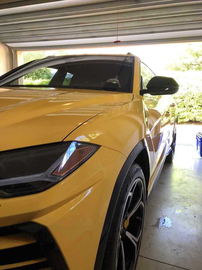 A yellow lamborghini urus is parked in a garage.