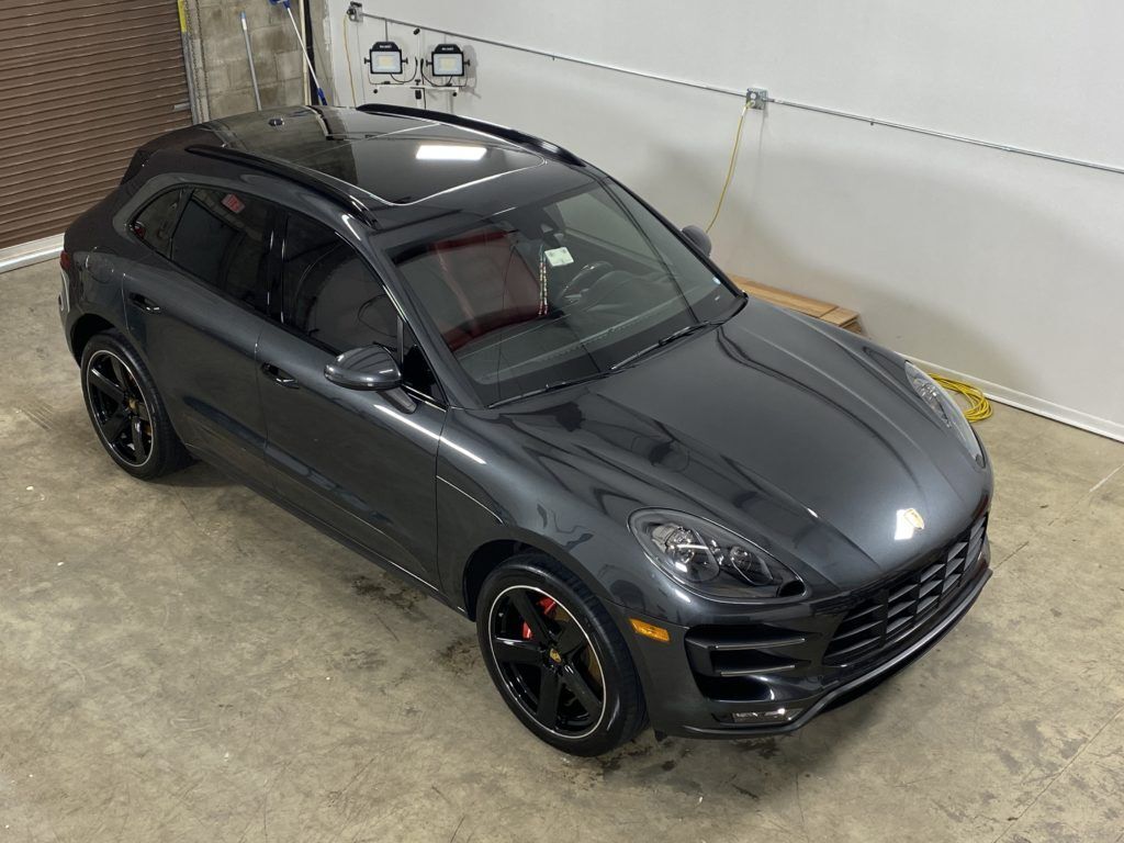 A gray porsche macan is parked in a garage.