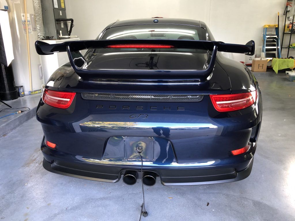 A black porsche 911 gt3 is parked in a garage.