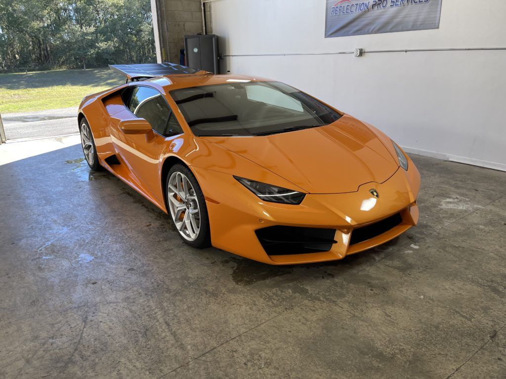 An orange lamborghini huracan is parked in a garage.