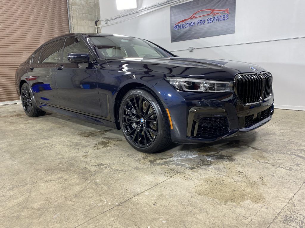 A black bmw 750li is parked in a garage.