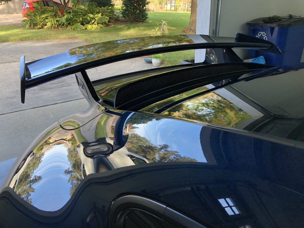 A car with a spoiler on the roof is parked in a garage.