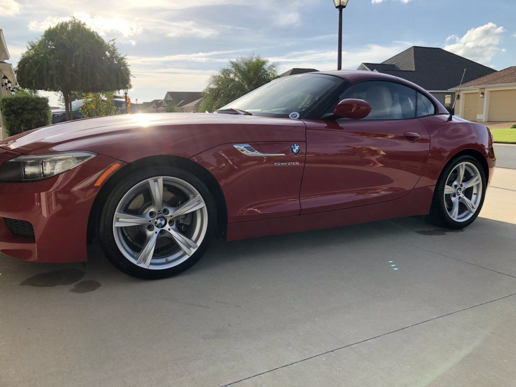 A red bmw z4 is parked in a driveway.