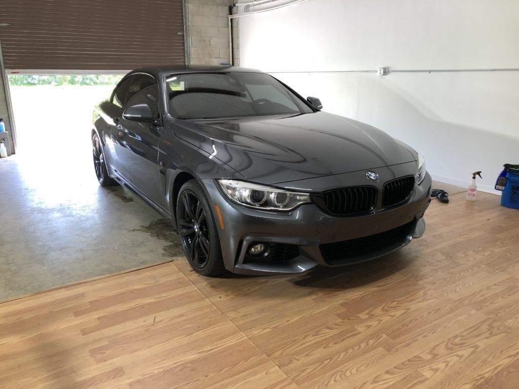 A bmw is parked in a garage with a wooden floor.