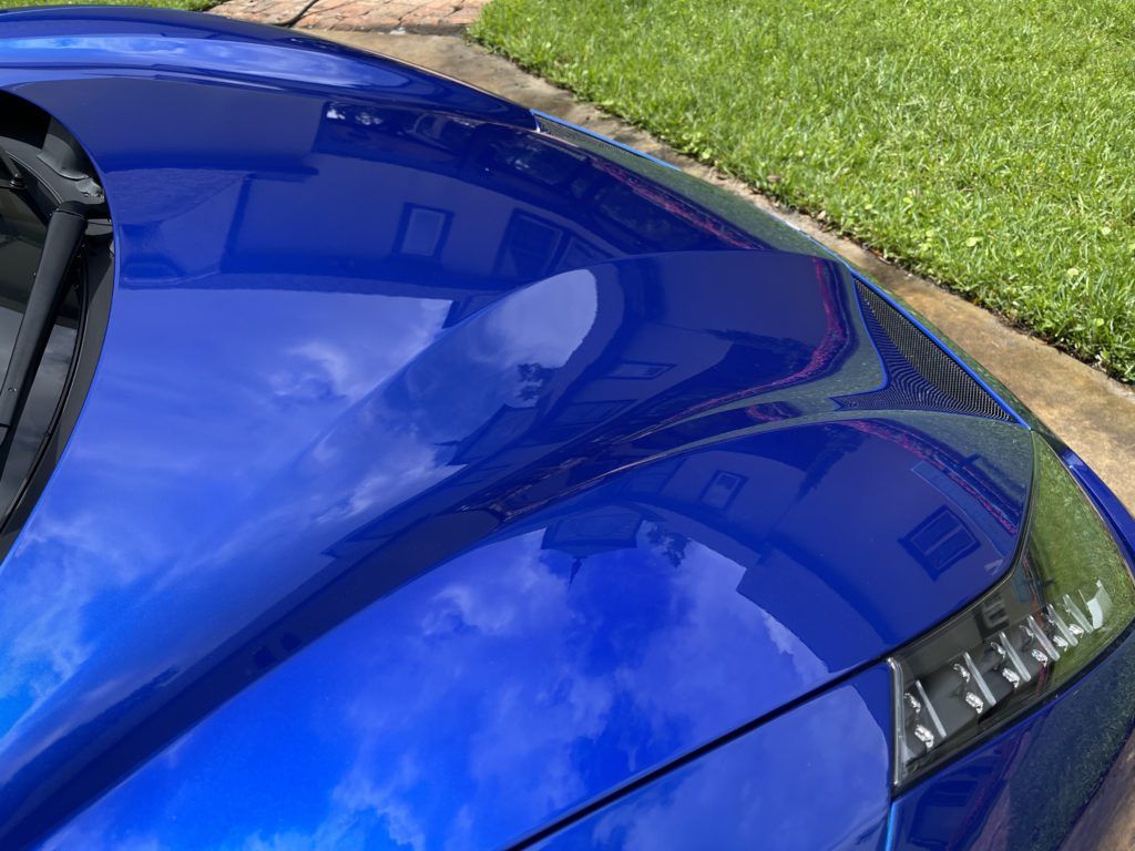 The hood of a blue car is reflected in the windshield.