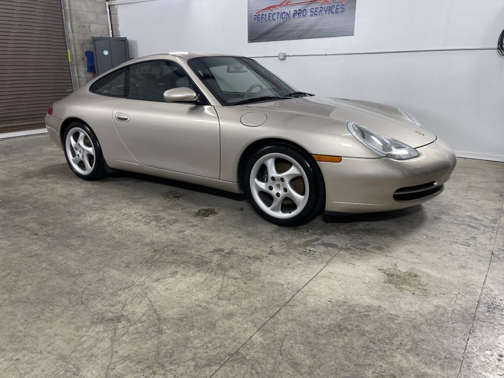 A silver porsche 911 is parked in a garage.