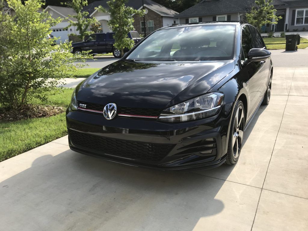 A black volkswagen golf gti is parked in a driveway.