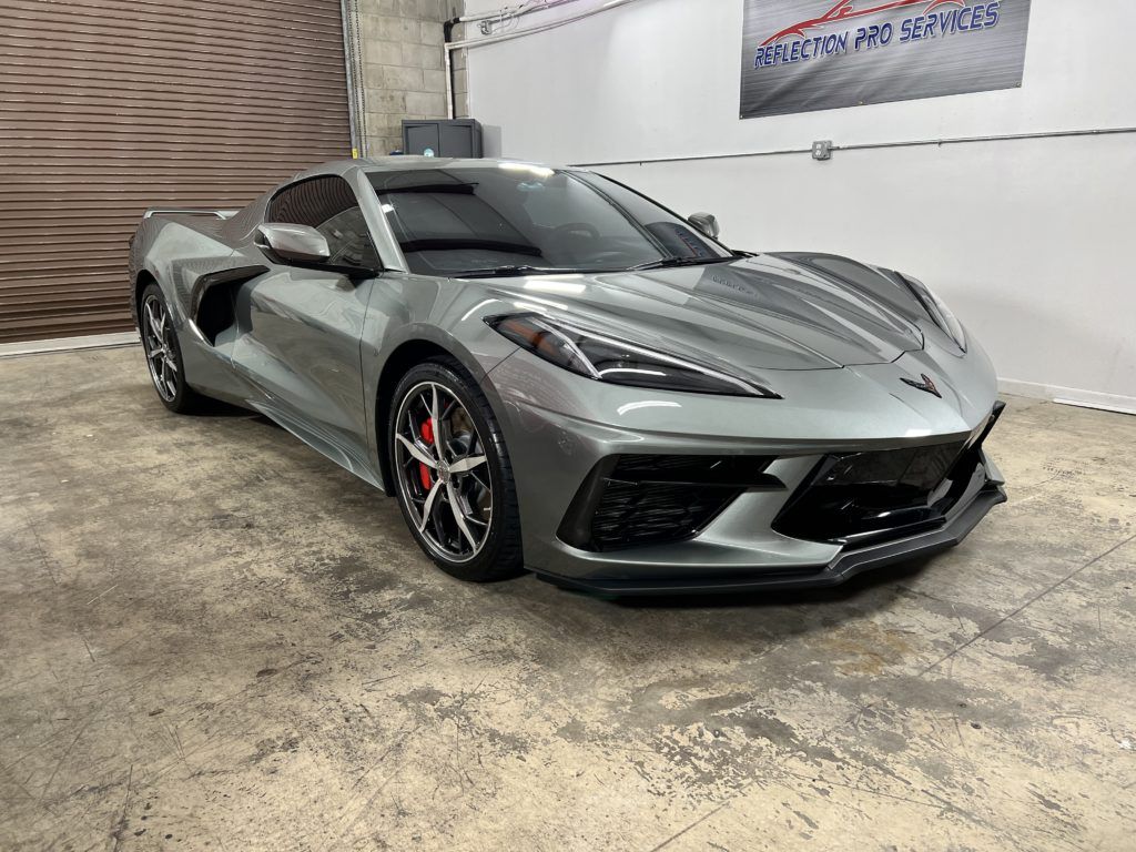 A gray corvette is parked in a garage.