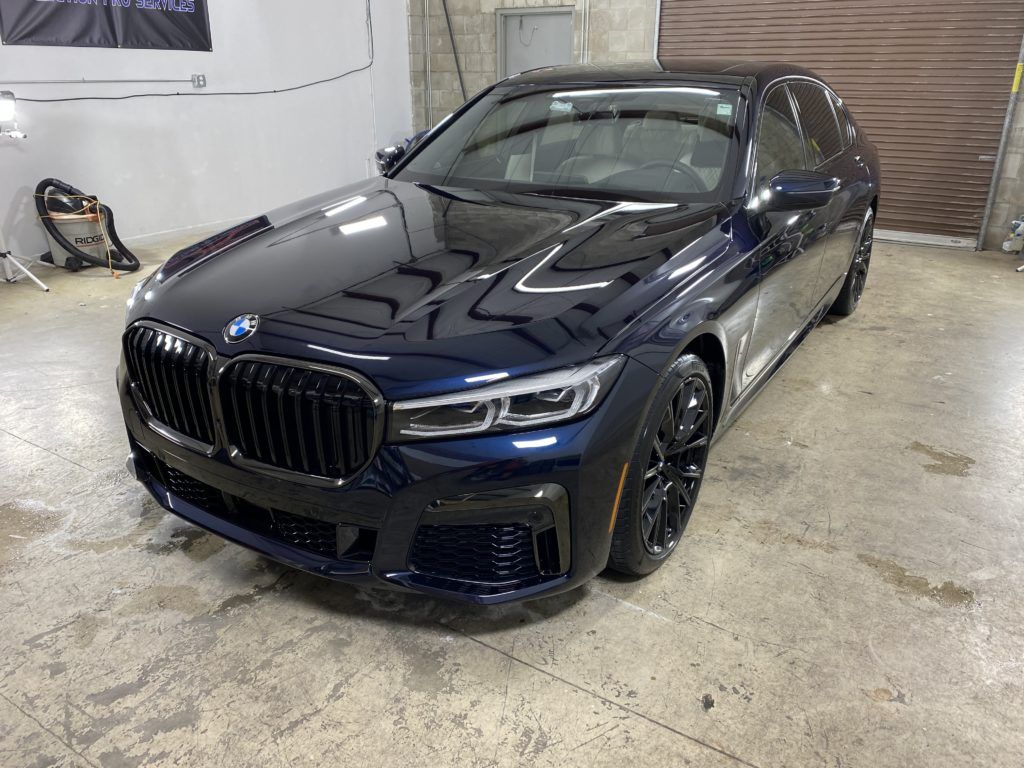 A blue bmw 7 series is parked in a garage.