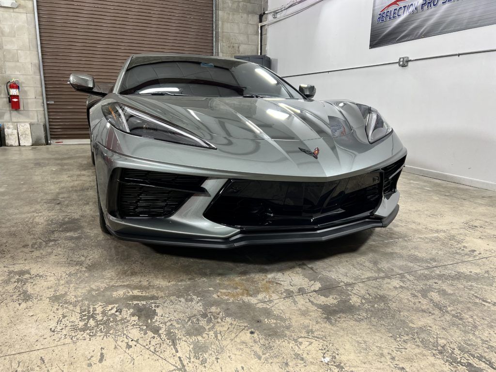 A gray sports car is parked in a garage.