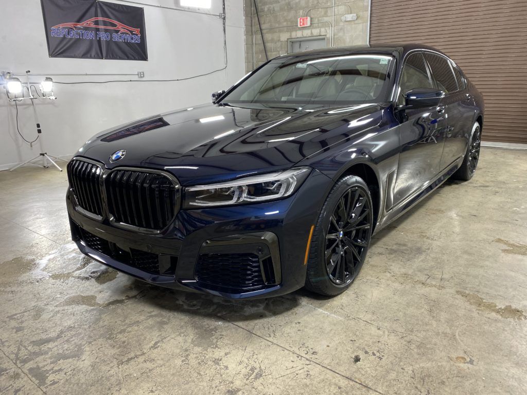 A black bmw 750li is parked in a garage.