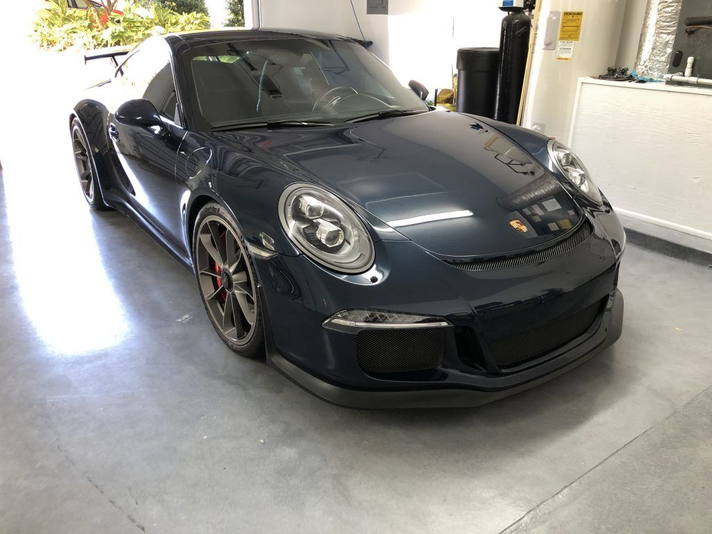 A black porsche 911 is parked in a garage.