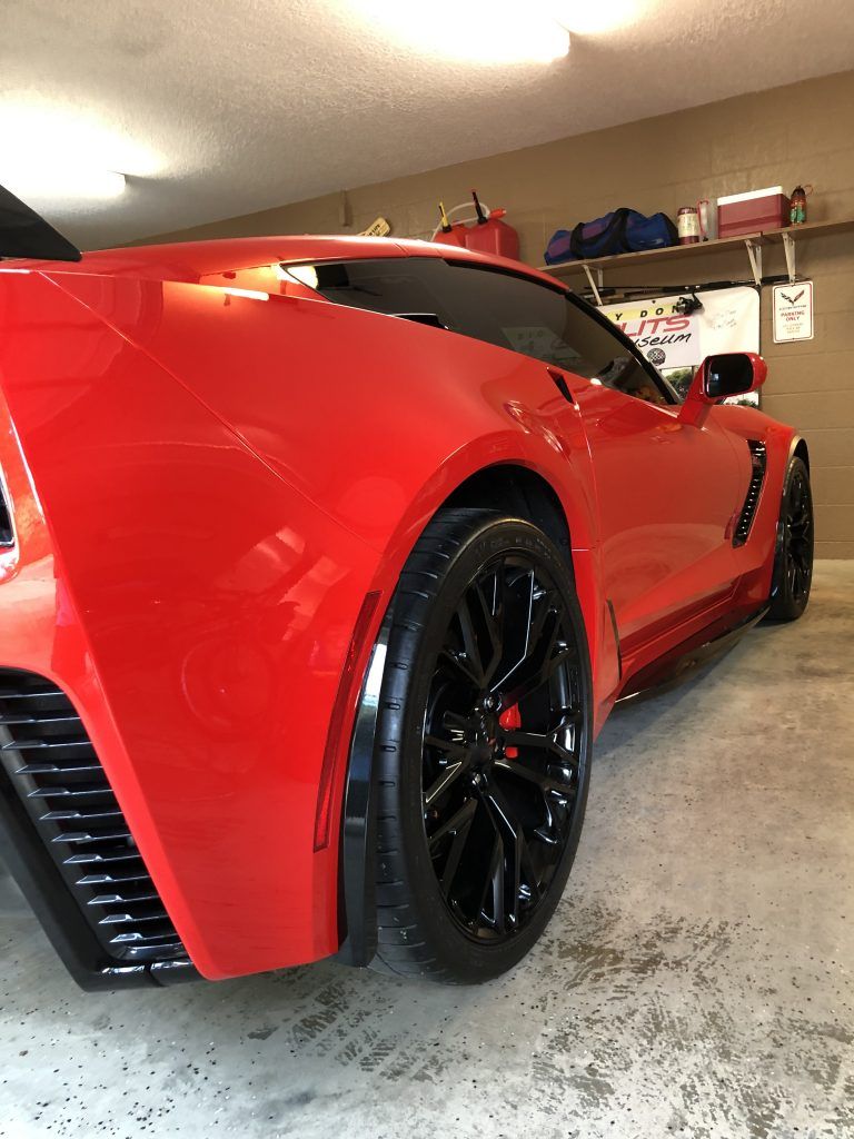 A red sports car is parked in a garage.