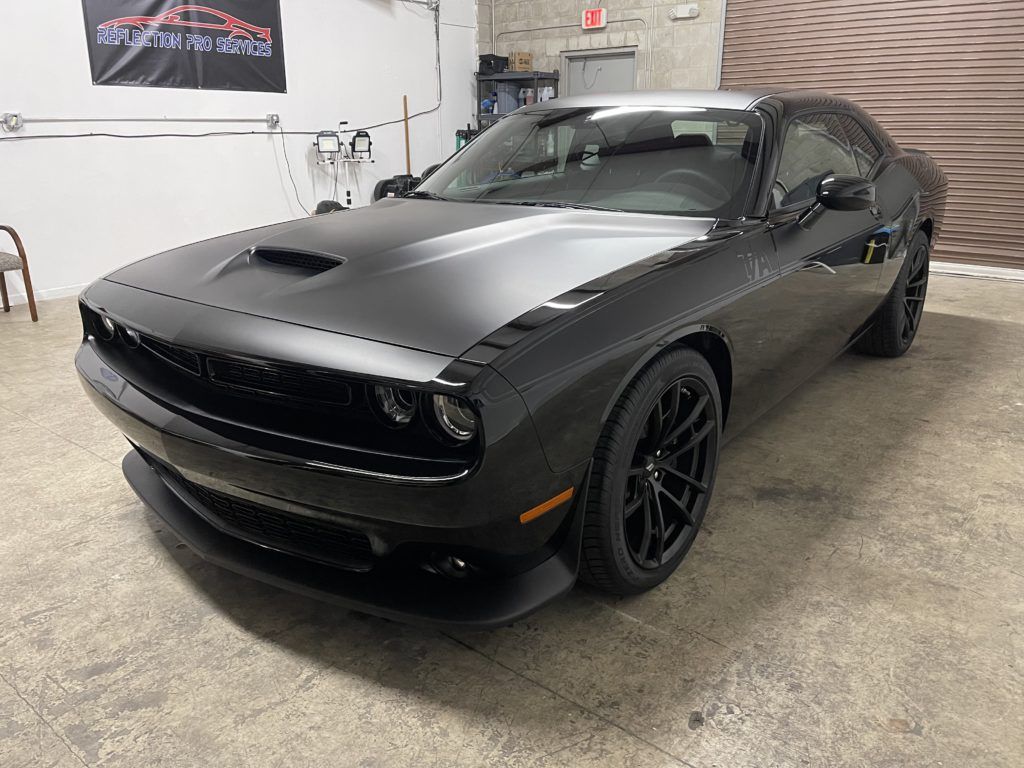 A black dodge challenger is parked in a garage.