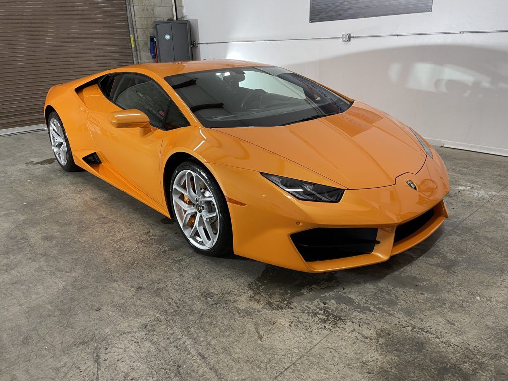 An orange lamborghini huracan is parked in a garage.