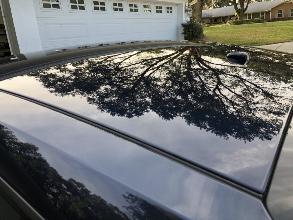 A black car is parked in front of a white garage door