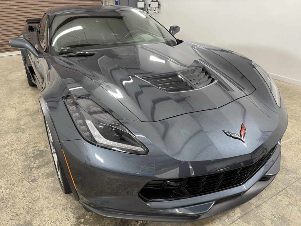 A gray corvette is parked in a garage.