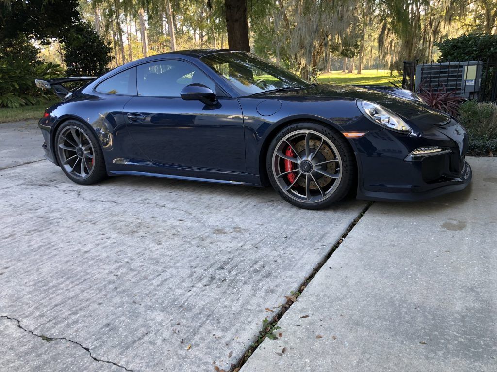 A blue porsche 911 gt3 is parked in a driveway.